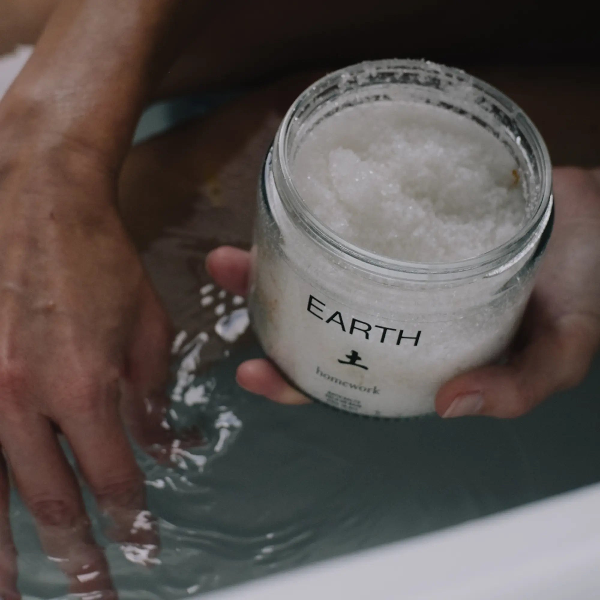 Person holding a jar of Homework Bath Salts labeled &