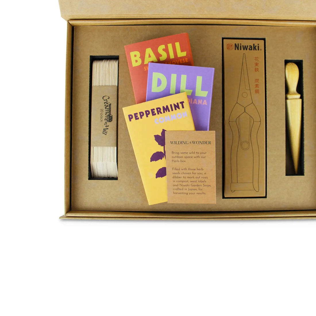 An inside view of the Limited Edition: Grow Your Own Herbs Kit by Wilding and Wonder, showing wooden seed labels, seed packets, Niwaki garden snips and a mini dibber.