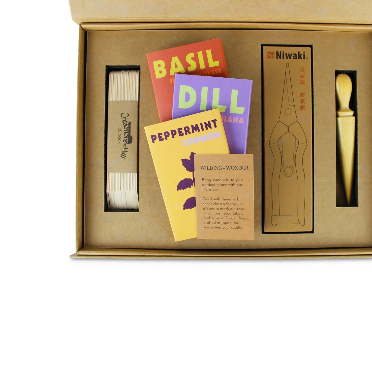An inside view of the Limited Edition: Grow Your Own Herbs Kit by Wilding and Wonder, showing wooden seed labels, seed packets, Niwaki garden snips and a mini dibber.
