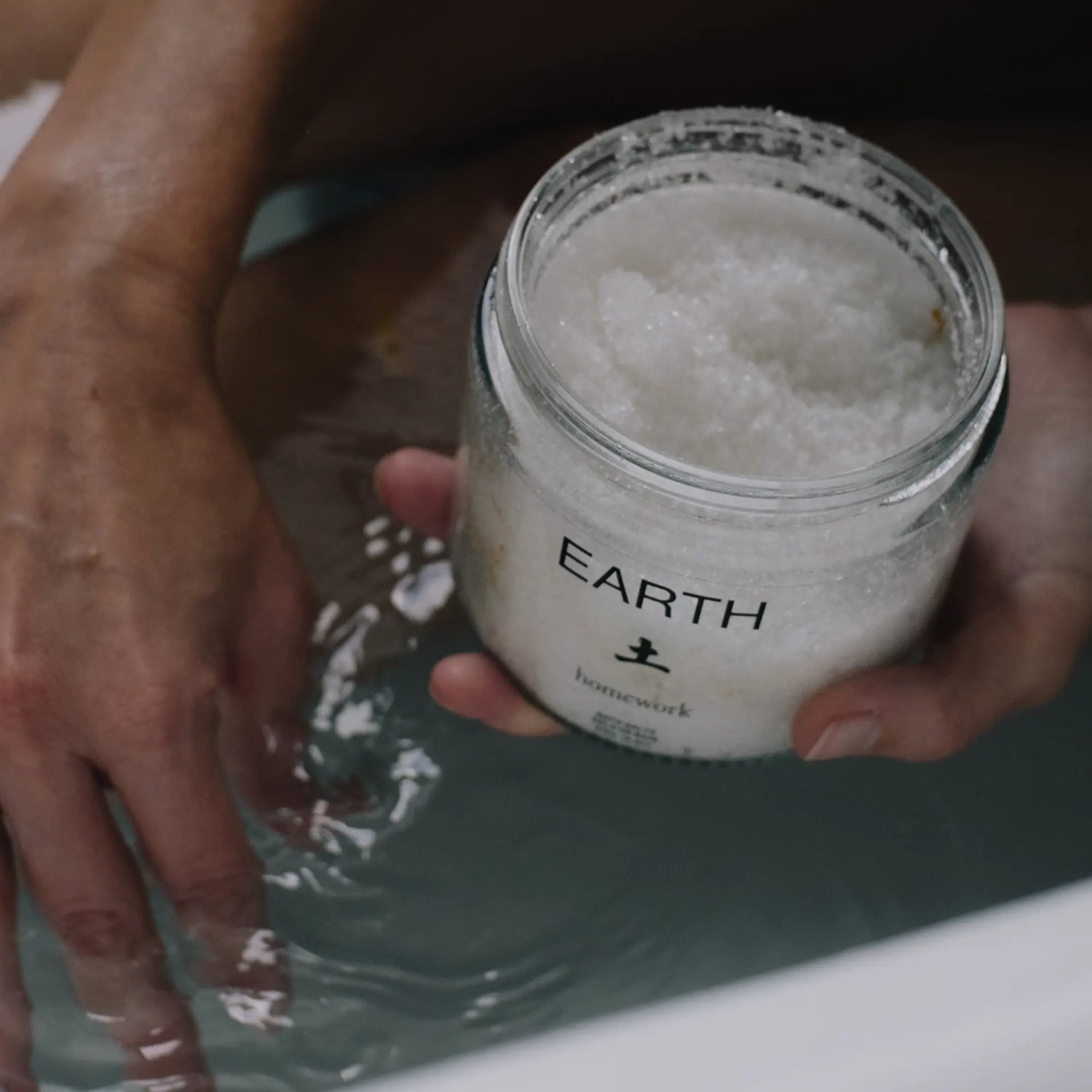 Person holding a jar of Homework Bath Salts labeled &